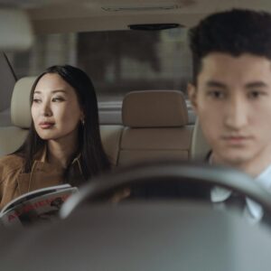 Asian businesswoman and male chauffeur in a luxury car interior, representing travel comfort and professional transportation.